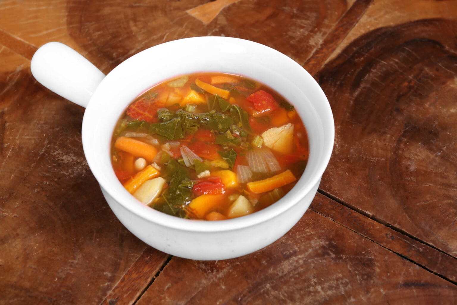 A bowl of soup on top of a wooden table.