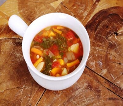 A bowl of soup on top of a wooden table.