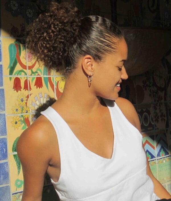 A woman with a ponytail in front of a wall.